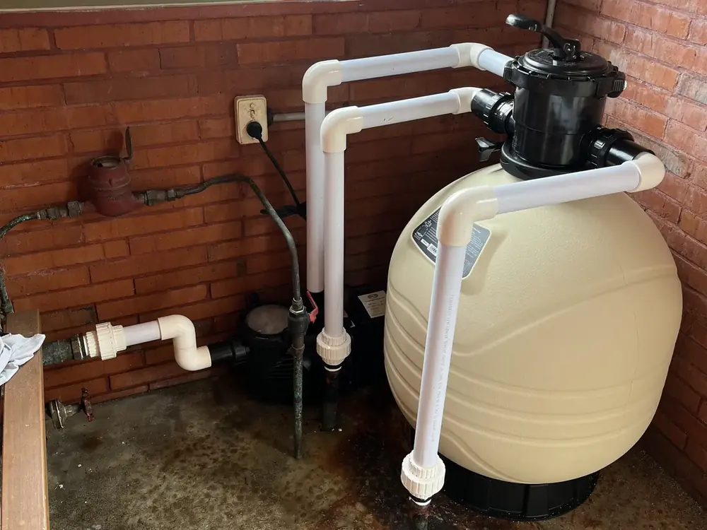 A newly installed pool sand filter and multiport valve, plumbed in white PVC beside the pump
